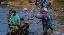 Petugas PLN bersama warga bahu-membahu membawa panel surya melintasi sungai. Upaya ini menjadi bagian dari perjalanan Program Listrik Desa (Lisdes) melalui SuperSUN dalam menghadirkan akses listrik bagi warga di Kecamatan Seko, Luwu Utara, Sulawesi Selatan.